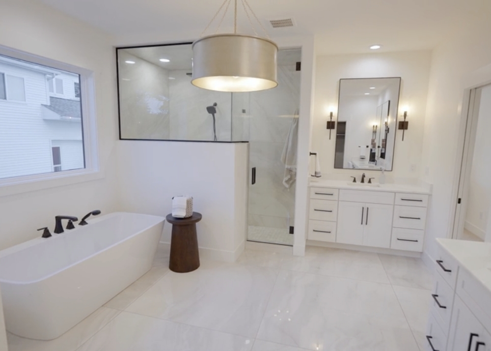 Parade of Homes 2022's master bathroom walk-in glass shower, vanity, and soaker tub